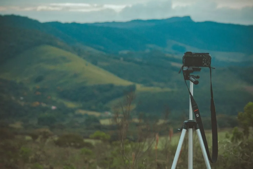 A camera on a tripod overlooking a green mountain valley.